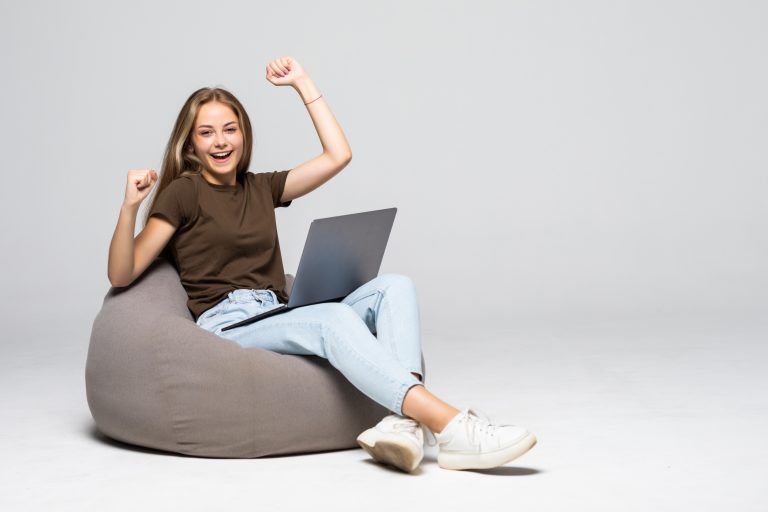 Una giovane donna seduta su un pouf con un portatile